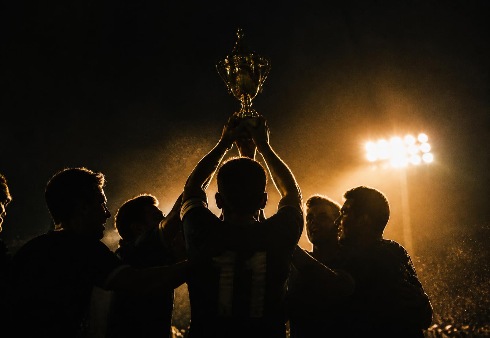 Flagler Soccer champions lifting the trophy under the floodlights